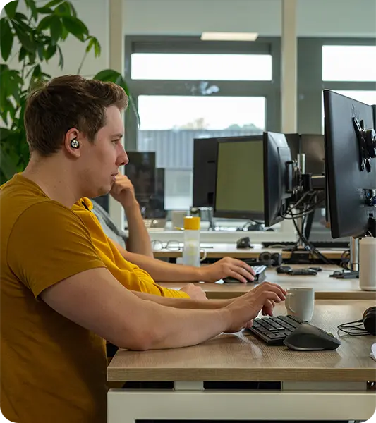 Developer van KJ Software aan het werk achter twee schermen